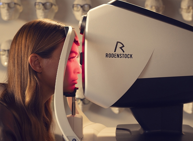 Una donna seduta davanti allo scanner DNEye durante la misurazione della vista